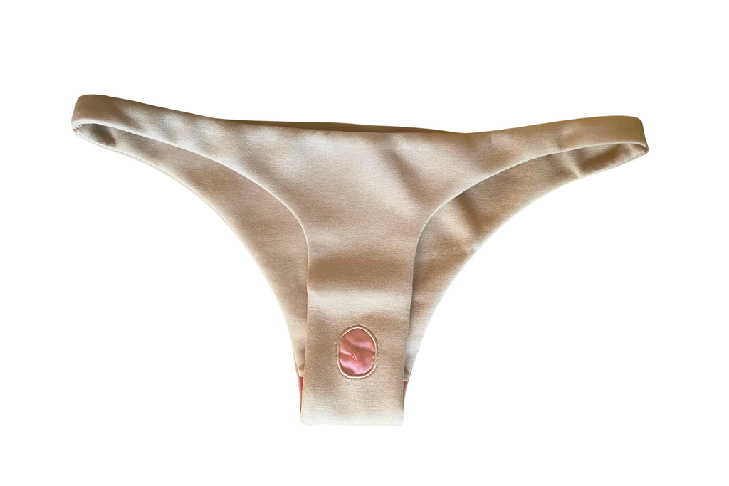 Beige minimal low waist panty with a pink detail and red pearl inside on a white background